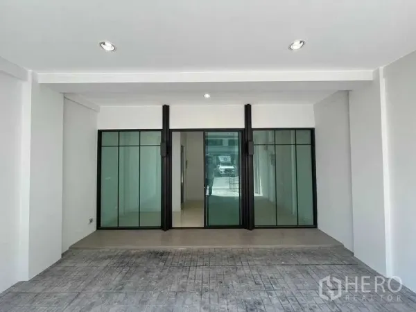 带办公室的家 出租 - 有顶停车区，通向黑色框架的玻璃推拉门入口。