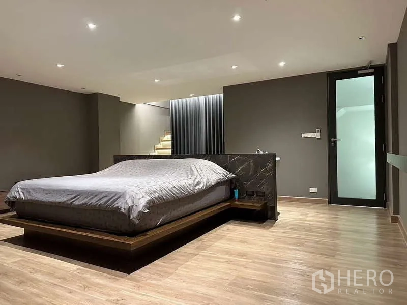 Townhouse for rent in Yan Nawa, Bangkok - Master bedroom with platform bed, recessed lighting and wood floors.