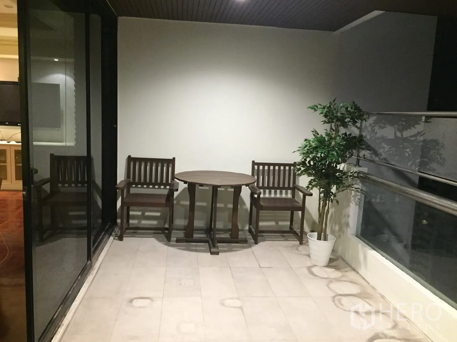 公寓 出租在Watthana, Bangkok - 带顶阳台，放置两把木椅、一张圆桌和绿植，可望城市景致。