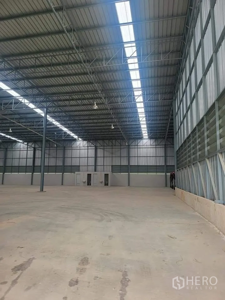 Warehouse for rent in Lat Krabang, Bangkok - Interior view toward the end wall with high ceiling, skylight strip, and utility rooms.