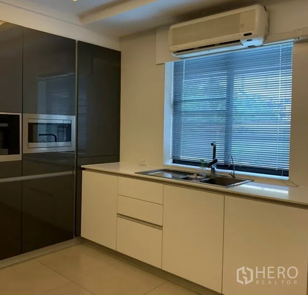 Detached House for rent in Din Daeng, Bangkok - Bright kitchen with sink under a window with blinds and a wall-mounted air conditioner.