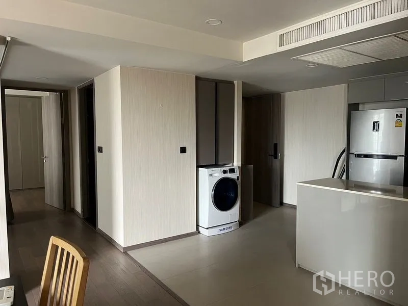 公寓 出租在Pathum Wan, Bangkok - 厨房旁的家务区，配置前置洗衣机、收纳柜与入户走廊。