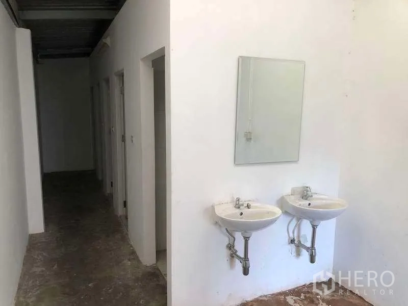 工厂 出租或出售在Bang Phli, Samut Prakan - 实用区设双壁挂洗手盆，旁为通往多间洗手间的走廊。