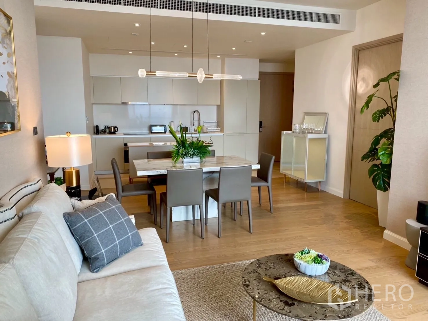 公寓 出租在Khlong San, Bangkok - 开放式客餐厅与白色厨房，配大理石餐桌和吊灯。