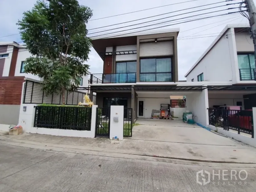 Detached House for sale in Samut Prakan - Modern two-storey detached house exterior with gated driveway and large windows.