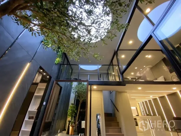 独立式住宅 出售在Watthana, Bangkok - 中庭上方圆形天窗，室内乔木与玻璃步道相映成景