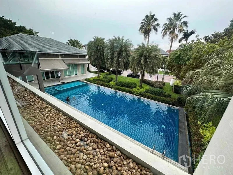 独立式住宅 出售在Saphan Sung, Bangkok - 小区大型游泳池，周围是棕榈树与景观花园。