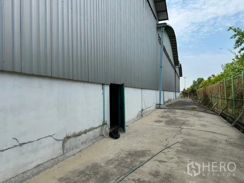 Warehouse for rent in Bang Pa-in, Phra Nakhon Si Ayutthaya - Side service lane beside the warehouse with metal cladding and a small access door.