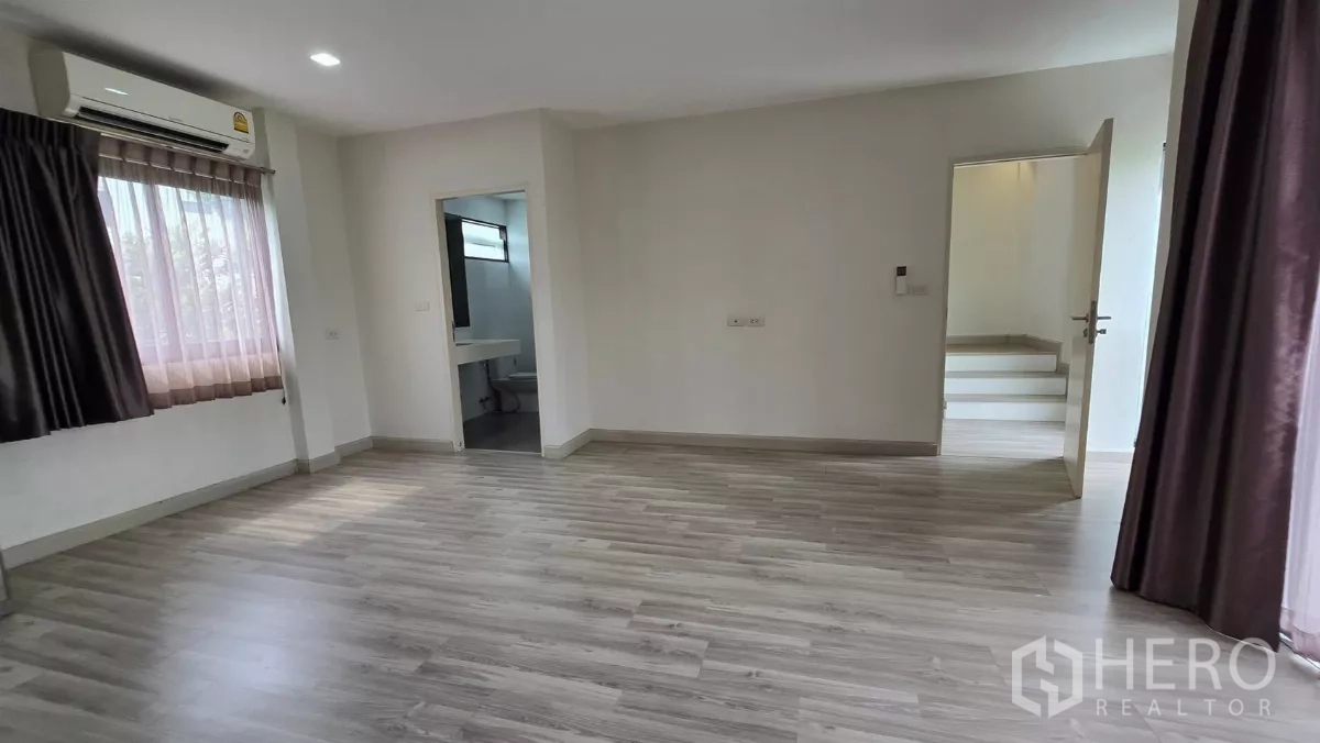 Townhouse for rent or sale in Saphan Sung, Bangkok - Master bedroom looking toward ensuite bathroom and windows with air conditioning.