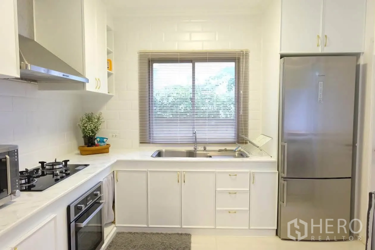 半独立式住宅 for rent or sale in Suan Luang, Bangkok - 明亮白色厨房，设燃气灶、烤箱、烟机、水槽与不锈钢冰箱。