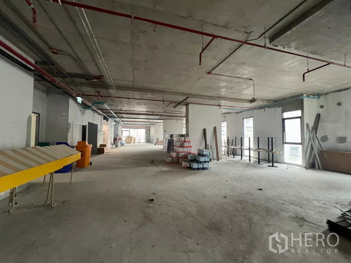 办公空间 出租在Khlong Toei, Bangkok - 狭长型楼层布局，多扇窗户，现场堆放建材与设备。