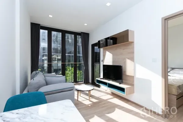 Condominium for rent in Watthana, Bangkok - Living area with wall-mounted media shelf, TV and sliding doors to the bedroom.