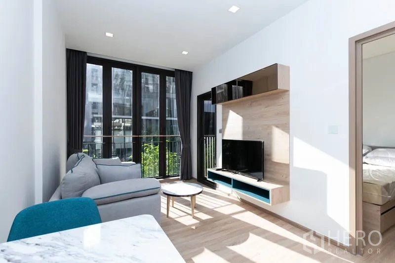 Condominium for rent in Watthana, Bangkok - Living area with wall-mounted media shelf, TV and sliding doors to the bedroom.