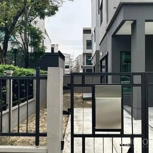 独立式住宅 出租在Khan Na Yao, Bangkok - 带大门的侧院与车道，邻近现代住宅。