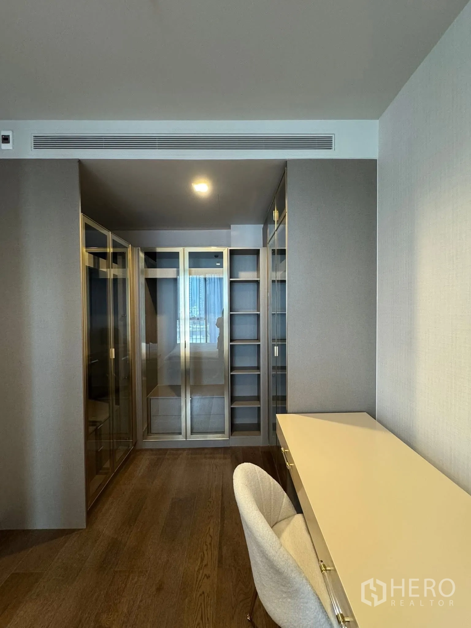 Condominium for rent in Khlong Toei, Bangkok - Walk-in wardrobe and study nook with built-in shelves and glass closets.