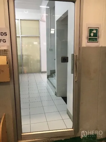 Factory for rent in Khlong Luang, Pathum Thani - Glass door entry leading to a tiled lobby and staircase inside the office block.