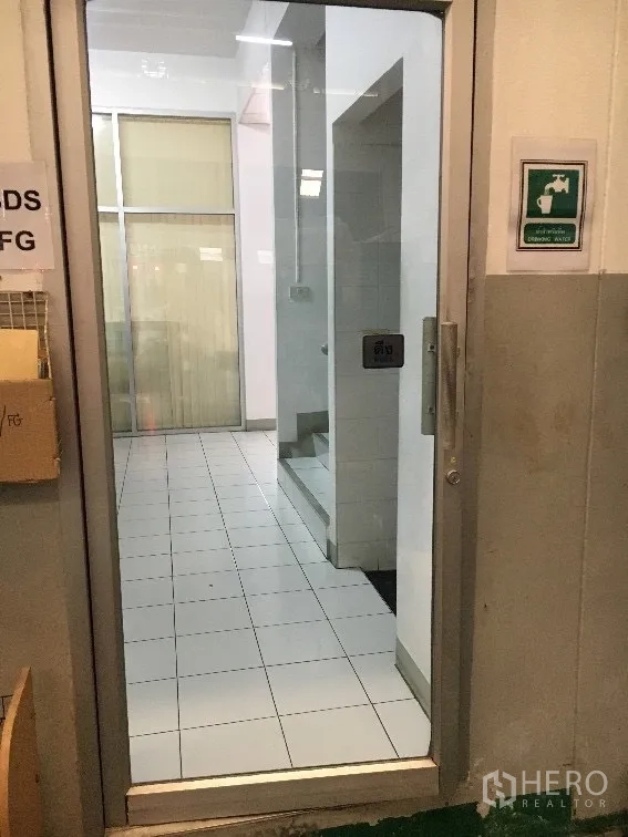 Factory for rent in Khlong Luang, Pathum Thani - Glass door entry leading to a tiled lobby and staircase inside the office block.