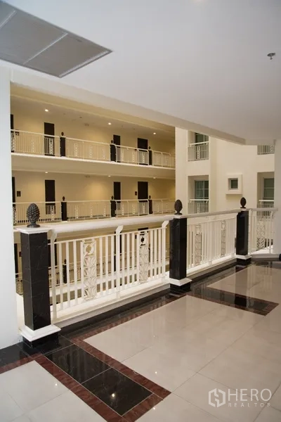 Condominium for rent in Khlong Toei, Bangkok - Neat condominium atrium corridor with white railings and polished floors.