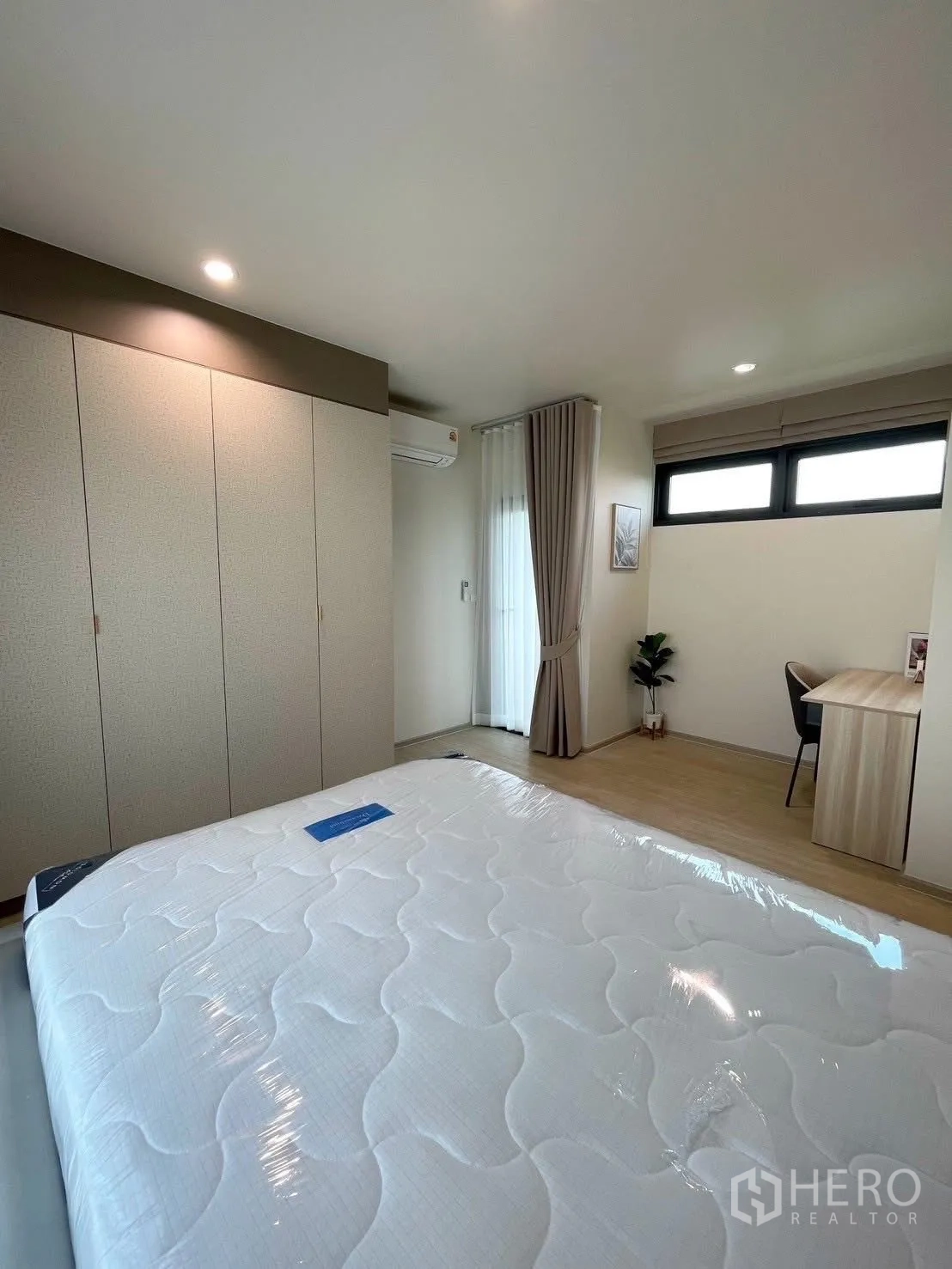 บ้านเดี่ยว for rent in Bang Phli, Samut Prakan - ห้องนอนหลักพร้อมตู้เสื้อผ้ายาวเต็มผนัง เตียงบุนวม แอร์ และมุมทำงาน