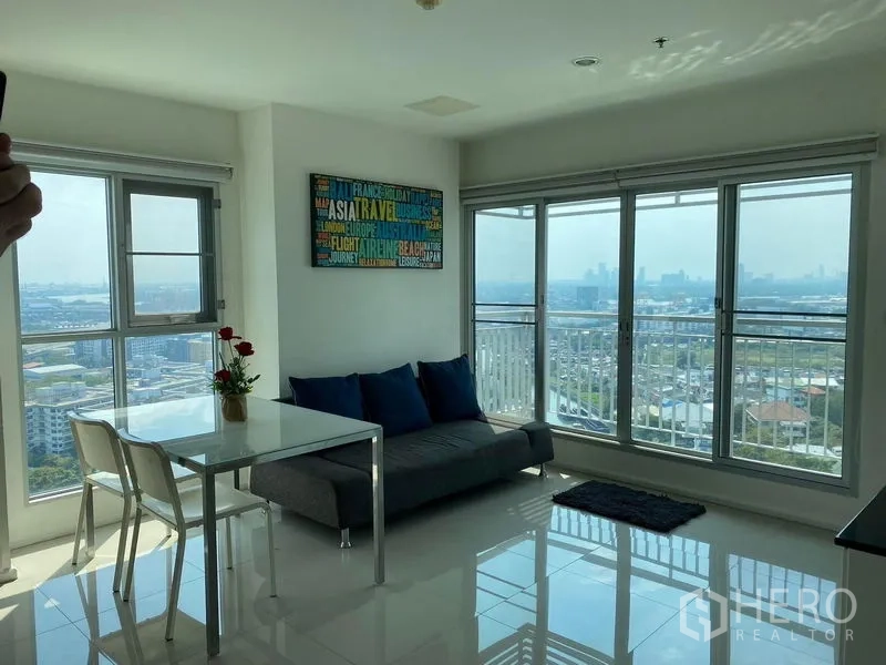 Condominium for sale in Khlong Toei, Bangkok - Living area with sofa, dining table and balcony access facing panoramic skyline.