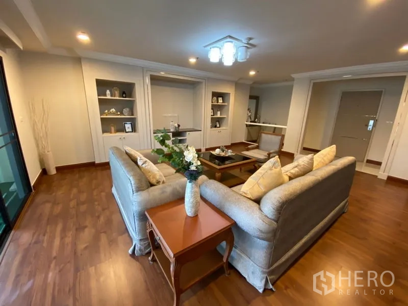 Condominium for rent in Watthana, Bangkok - Cozy living room with sofa set, built-in display shelves, and wide balcony access.
