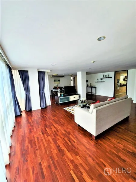 Condominium for rent in Bang Rak, Bangkok - Open-plan living area with sofa, media console, and full-height windows.