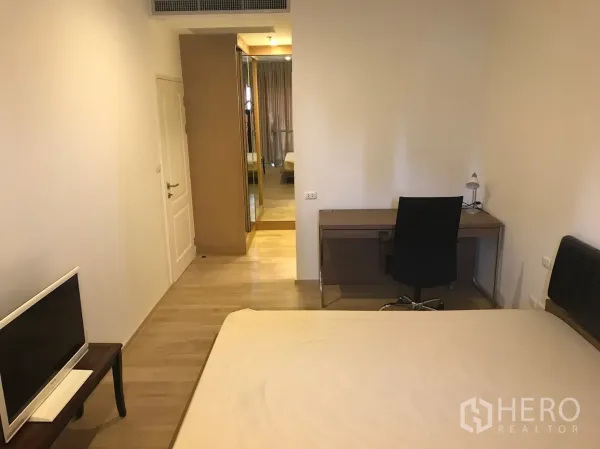 Condominium for rent in Bangkok - Bedroom with wood flooring, mirrored wardrobe, work desk and chair in a Khlong Toei condominium.