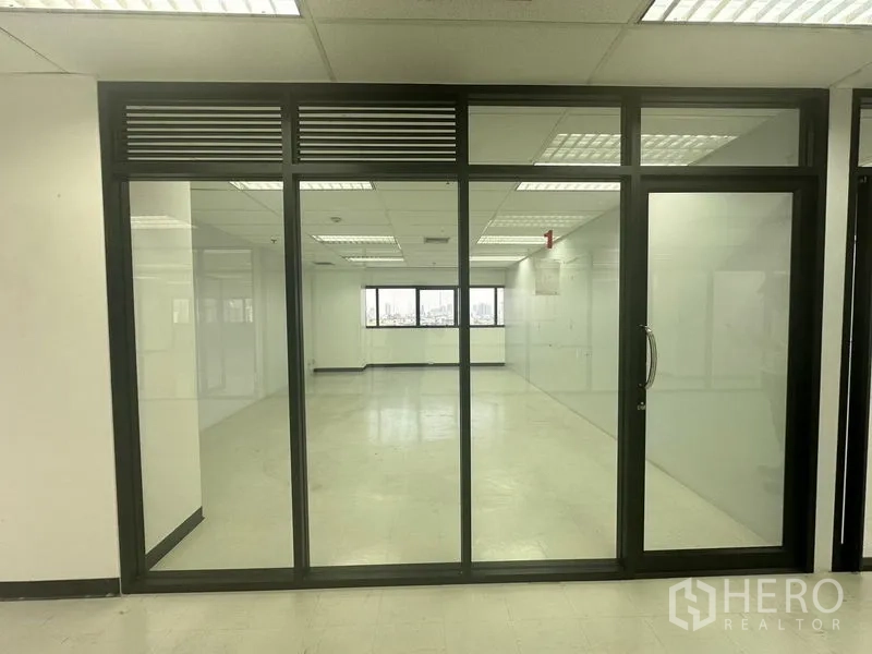办公空间 出租在Phaya Thai, Bangkok - 明亮的开放式办公室，黑色框架玻璃隔断与面向城市的窗户。