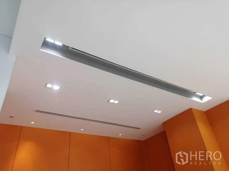 Office Space for rent in Pathum Wan, Bangkok - Recessed lights and long air-conditioning vent above orange-accented office walls.
