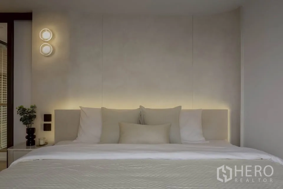 Condominium for rent in Khlong Toei, Bangkok - Bedroom with upholstered headboard, warm backlighting, and minimal decor.