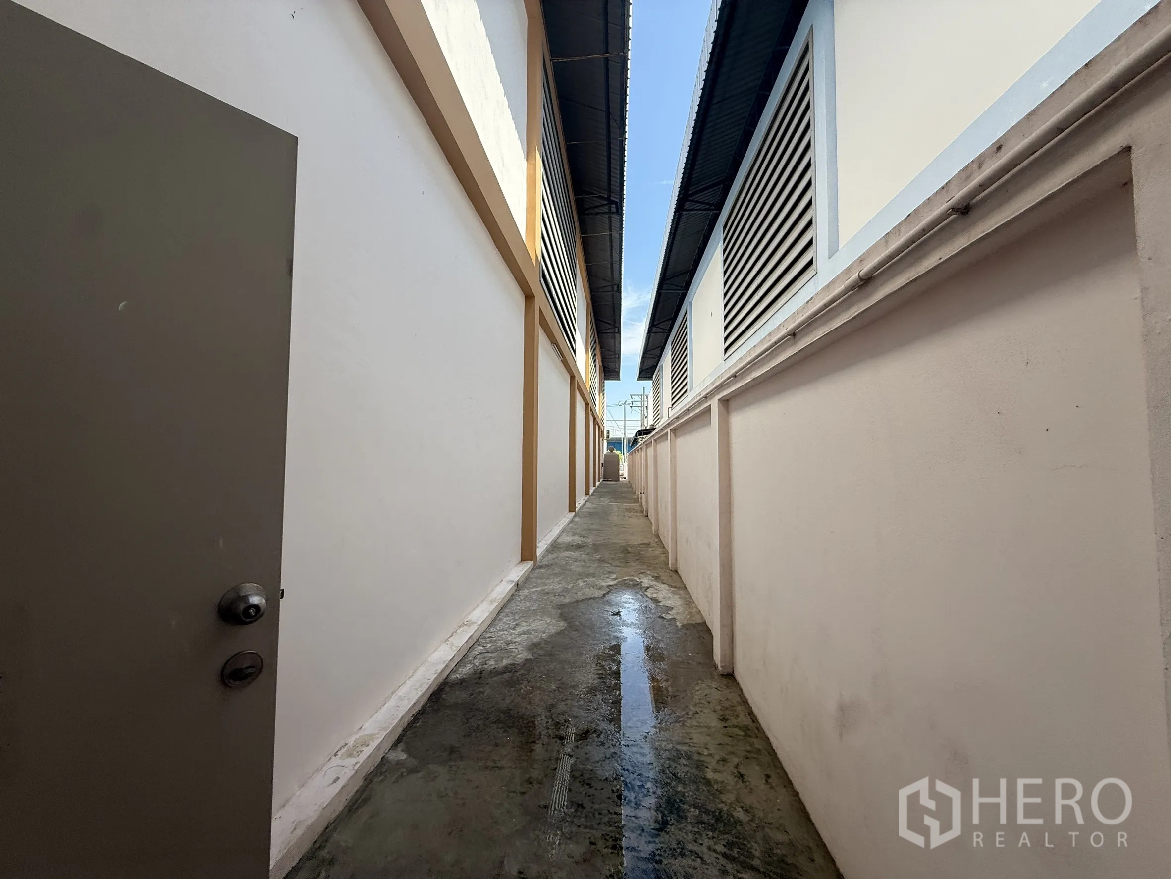 Warehouse for rent or sale in Bang Bo, Samut Prakan - Narrow exterior passageway between buildings with vents and drainage.