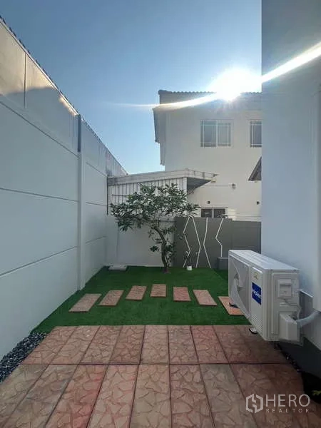 Detached House for rent in Bang Kapi, Bangkok - Rear courtyard with small lawn, stepping stones and an AC unit.