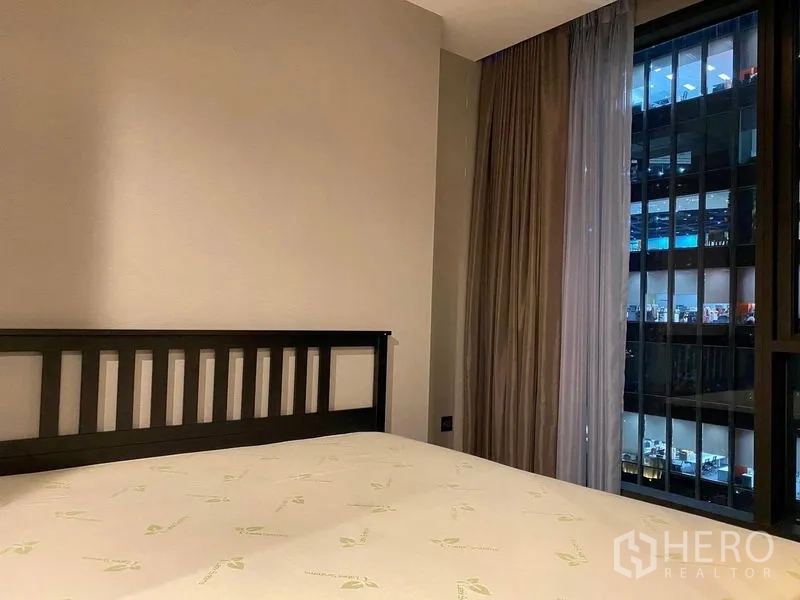 公寓 出租在Huai Khwang, Bangkok - 卧室配床架与通高窗，可赏夜间城市景观与遮光窗帘。