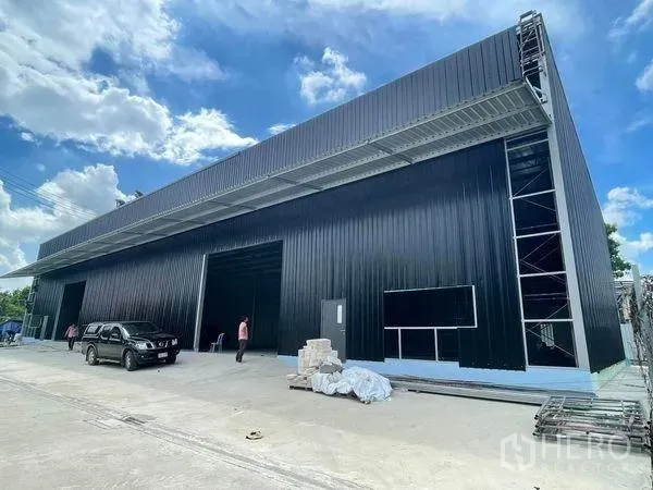 Warehouse for rent in Pak Kret, Nonthaburi - Brand-new black metal warehouse exterior with wide canopy, loading bays and parking area.