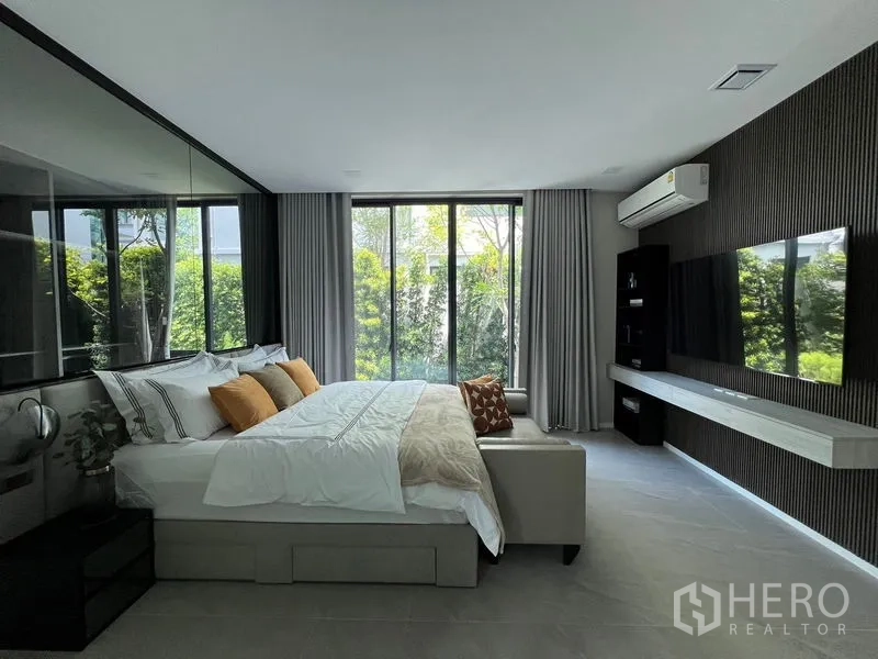 Detached House for rent in Saphan Sung, Bangkok - Garden-view bedroom with wall-mounted TV, split AC and large windows.