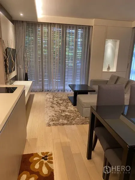 Condominium for rent in Watthana, Bangkok - Open‑plan kitchen and living space with light wood floors, coffee tables, and expansive windows.