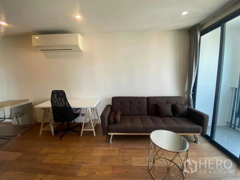公寓 出租或出售在Ratchathewi, Bangkok - 工作角落配书桌，邻近沙发与阳台玻璃门。
