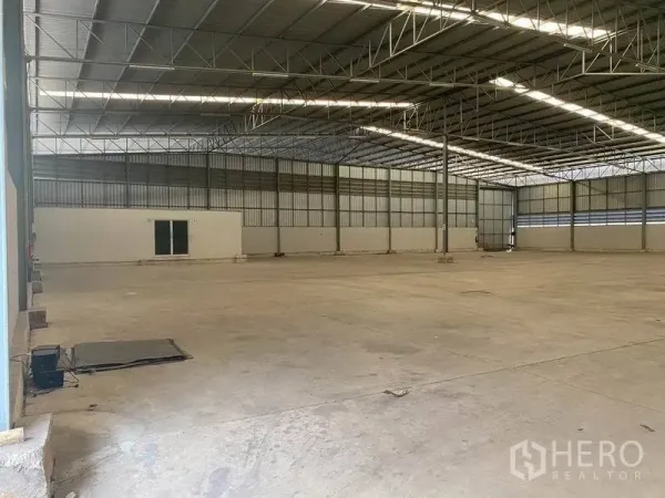 货栈 出租在Lat Krabang, Bangkok - 宽敞仓库内景，高钢结构屋顶、混凝土地面与小型办公室