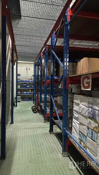 Warehouse for rent or sale in Bangkok Yai, Bangkok - Aisle with industrial racking and boxed inventory inside secure warehouse.