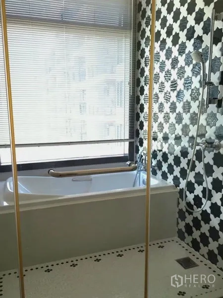 Condominium for rent in Khlong Toei, Bangkok - Bathroom featuring a soaking tub by the window and black-and-white patterned shower tiles.