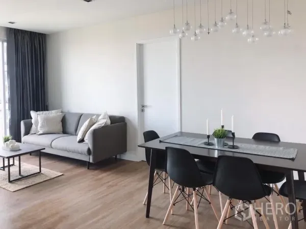 Condominium for rent in Bang Rak, Bangkok - Bright living and dining area with grey sofa, black dining set, pendant lights and wood flooring.