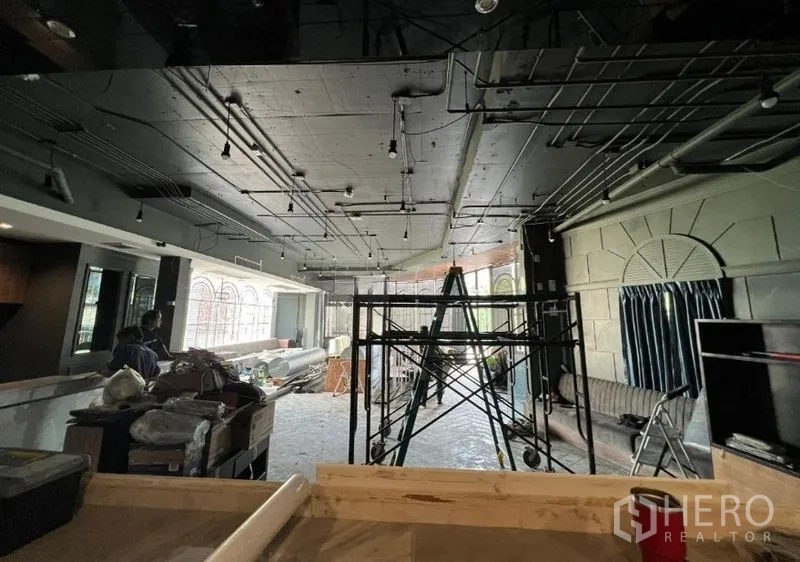 Retail Space for rent - Deep retail floorplate with exposed services and scaffold, windows lining one side.