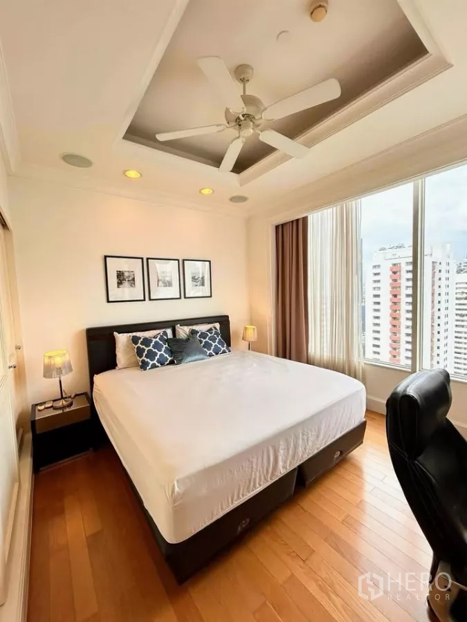 Condominium for sale in Watthana, Bangkok - Second bedroom with king bed, tray ceiling, recessed lighting and city skyline outlook.