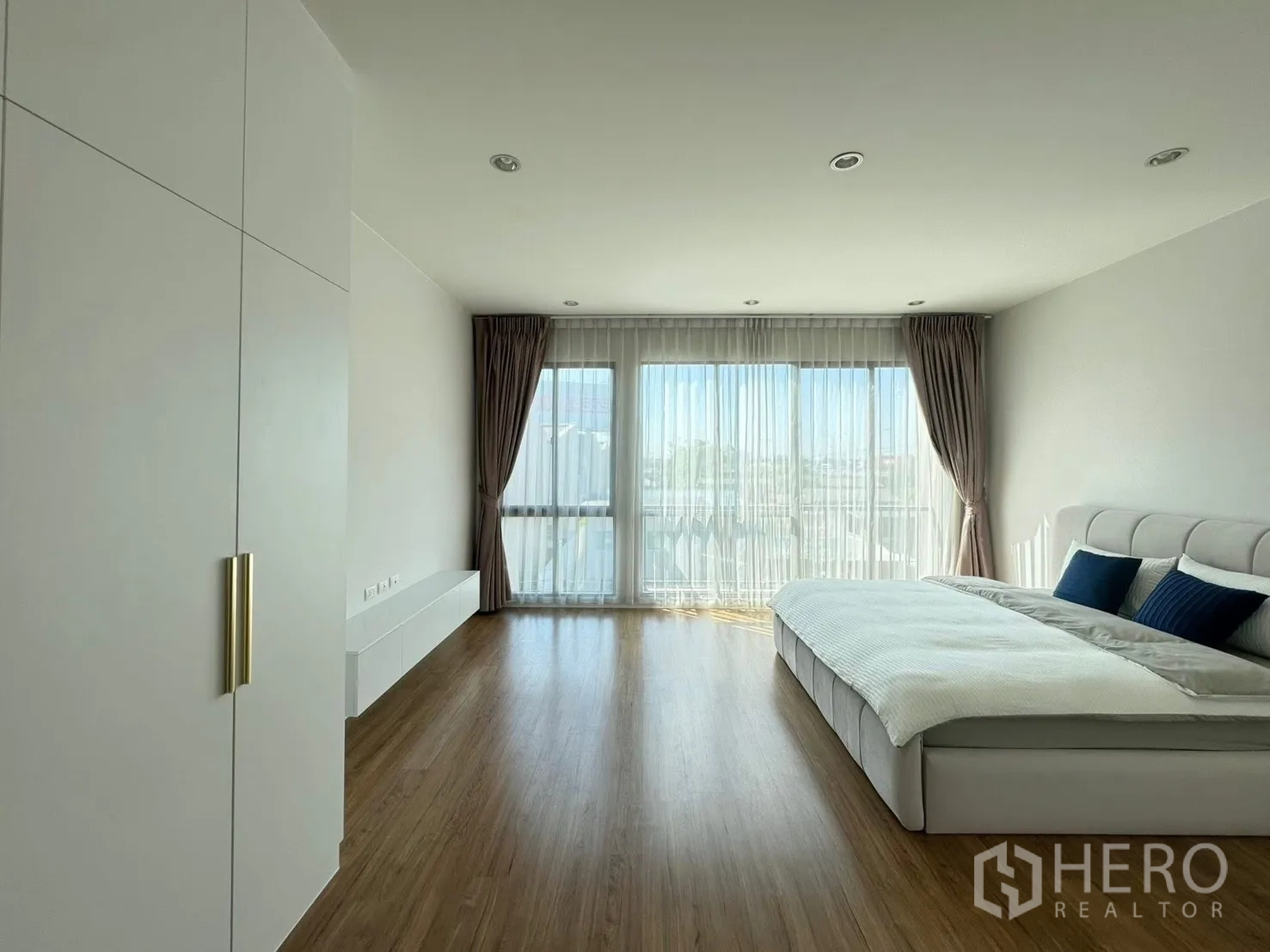 Townhouse for rent in Saphan Sung, Bangkok - Wide master bedroom facing full-height windows with sheer drapes.