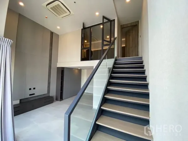 Condominium for sale in Pathum Wan, Bangkok - Staircase with glass balustrade leading to the mezzanine in a loft condo.