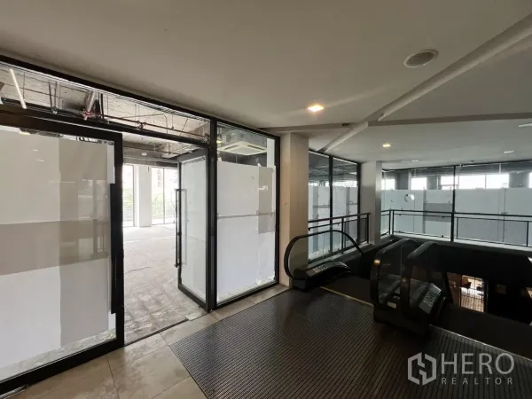零售空间 出租在Watthana, Bangkok - 二层零售入口，带扶梯和玻璃门。