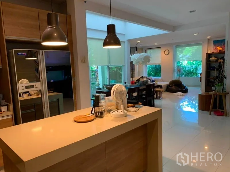 Detached House for sale in Suan Luang, Bangkok - View from the kitchen island to dining and living areas with pendant lights and large garden-facing windows.