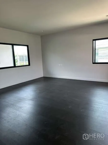 Detached House for sale in Lam Luk Ka, Pathum Thani - Large upstairs bedroom with dark wood flooring and windows.