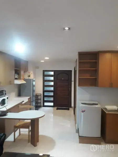 公寓 出租在Watthana, Bangkok - 开放式厨房，木质橱柜与餐吧台，靠近入户门并配家电。