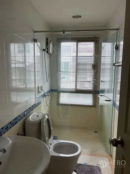Townhouse for rent in Saphan Sung, Bangkok - Second bathroom with glass shower screen, window and white sanitary ware.